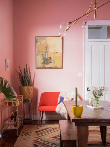 pink dining room with red settee and brass chandelier