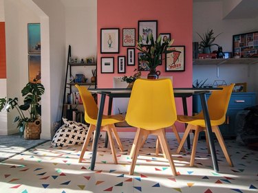 pink dining room idea with one accent wall and yellow chairs