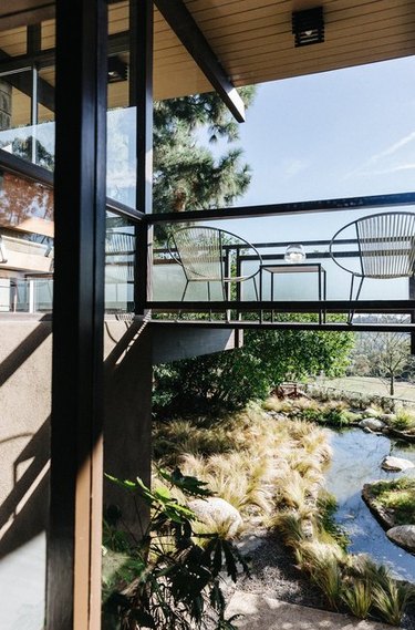 midcentury home with bridge-style balcony overlooking city and backyard stream