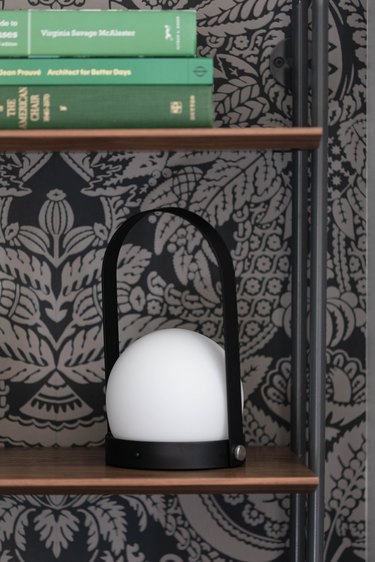 Menu portable LED lamp on bookcase next to patterned wallpaper