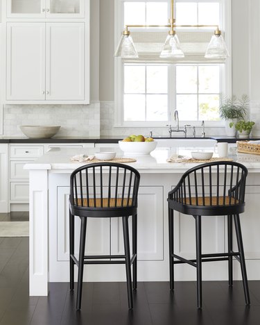 traditional kitchen lighting in white space with black stools