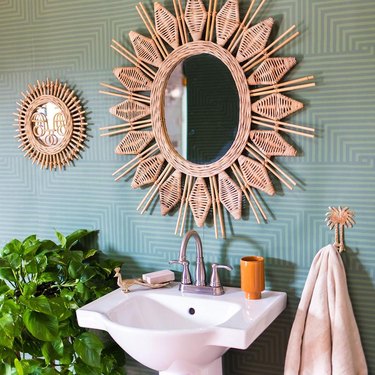 celadon colors in wallpaper in bathroom with rattan mirror