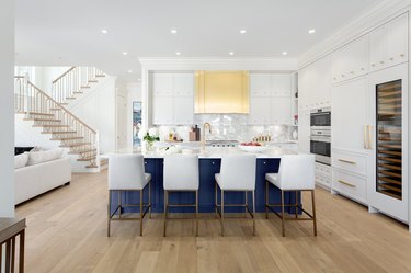 white kitchen with blue island and gold vent