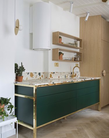 modern kitchen with green cabinets with brass detailing and terrazzo countertop