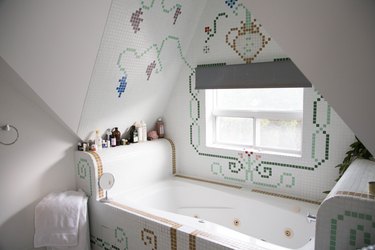 jetted tub with decorative tile surrounding it, bath products on the tub ledge