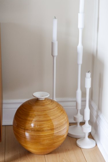 White tall candlesticks on floor with vase