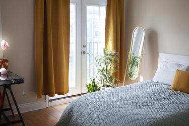 Идея спальни с драпировкой горчичного цвета, французскими дверями и синими постельными принадлежностями