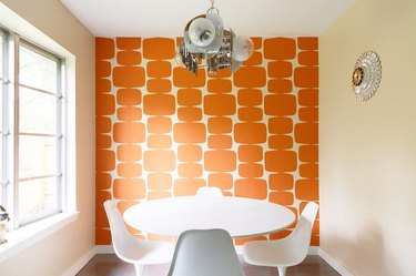 dining room area with orange wall and white chairs