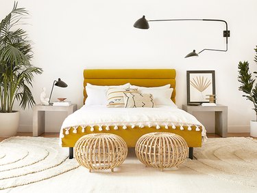 ochre color bed with white bedding and black wall sconce