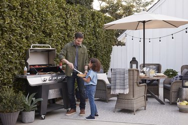 Father and daughter by grill outdoors