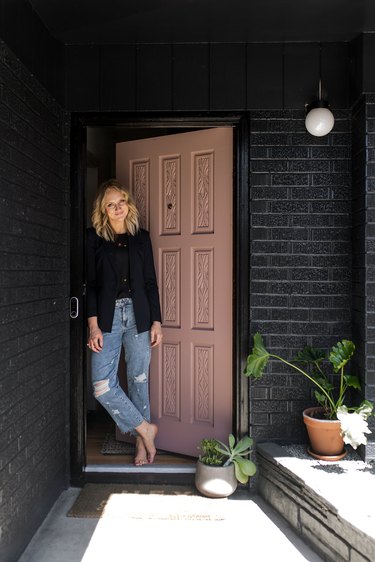 Kirsten Grove standing in front of front door and black brick wall with new Nest Hello System