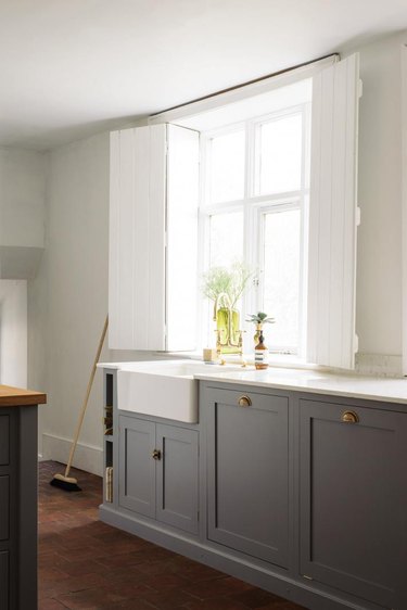 Farmhouse kitchen window with tall shutters and gray cabinets