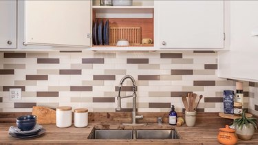 kitchen sink, wood countertop, open cabinet, patterned tile backsplash