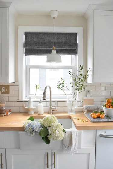 Farmhouse kitchen window with gray roman shades