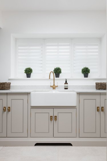 Kitchen window with tracked shutters in gray and white kitchen