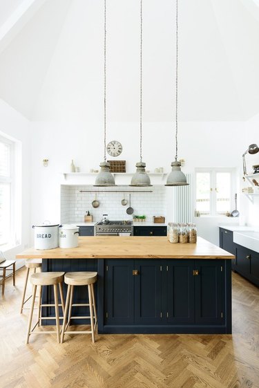 Traditional kitchen island with wood counter in kitchen with herringbone wood floors