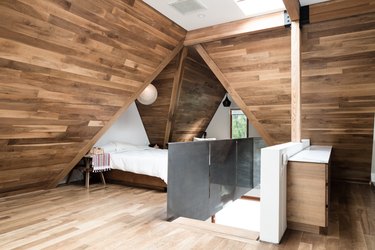 blonde wood floor in room with wood wall paneling