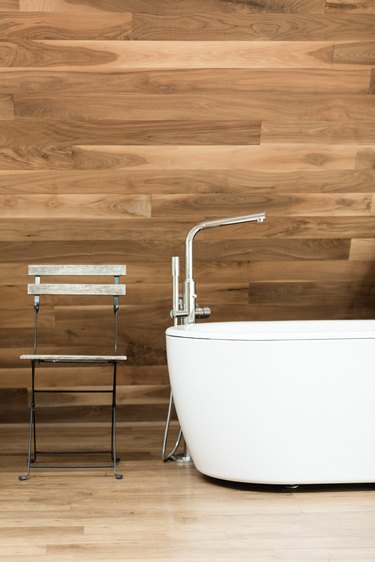 white stand-alone tub on wood floor; wood shiplap wall