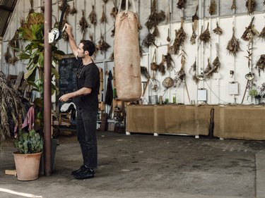 Florist Spencer Falls alongside flower bouquets hung on wall