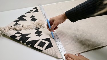 Marking a cut line on a rug for DIY Fringe Pillow Out of a Rug project