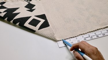 Marking a cut line on a rug for DIY Fringe Pillow Out of a Rug project