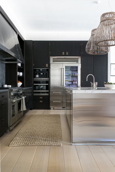 black kitchen cabinet idea for a modern kitchen with flloor-to-ceiling black cabinets, stainless steel appliances, and a stainless steel island