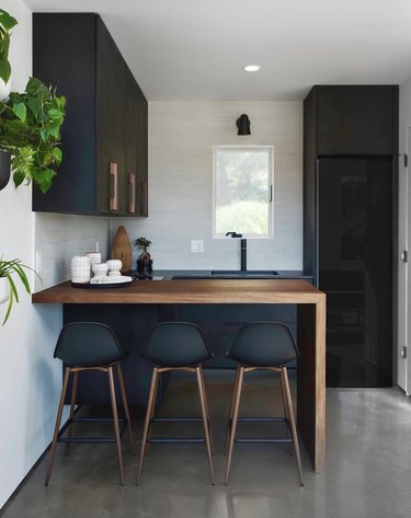 black kitchen cabinet idea for a small modern kitchen with matte black cabinets and a walnut waterfall countertop
