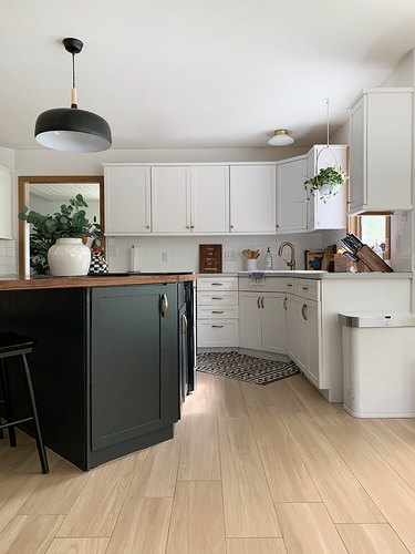 black kitchen cabinet idea for mostly white kitchen with a black island featuring a walnut countertop situated at an angle under a black pendant light