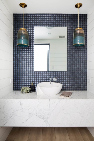 bathroom backsplash idea with navy square tile with frameless mirror and hanging pendant lights