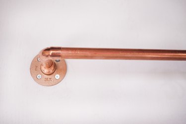 Copper pipe inserted into elbow fitting on wall