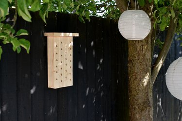 Bee house hanging on black garden fence