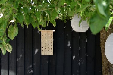 Wooden bee house on black garden fence