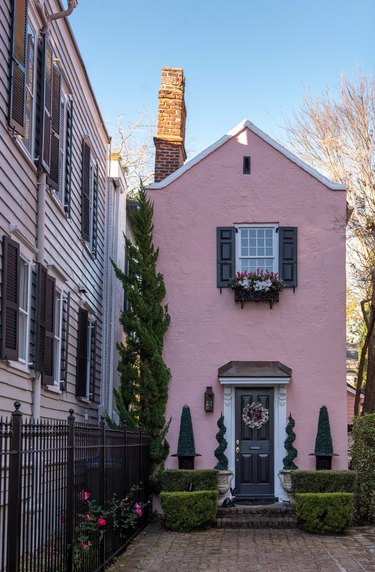 pink traditional stucco homes with topiaries and brick walkway