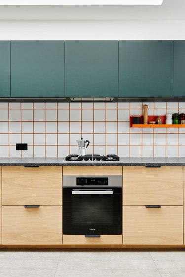 white tile kitchen backsplash with orange grout with green upper cabinets