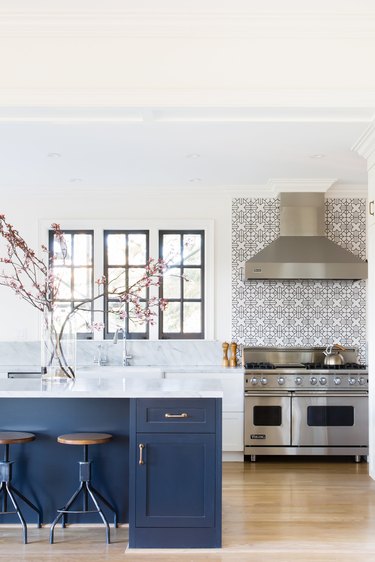 modern kitchen backsplash idea in light and bright space with blue cabinets and marble countertops