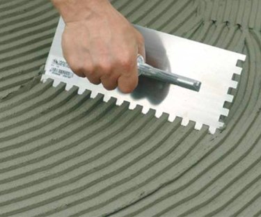 Spreading adhesive with a notched trowel.