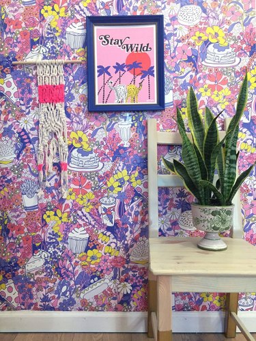 colorful wallpaper with a wall hanging, framed print, chair and plant nearby