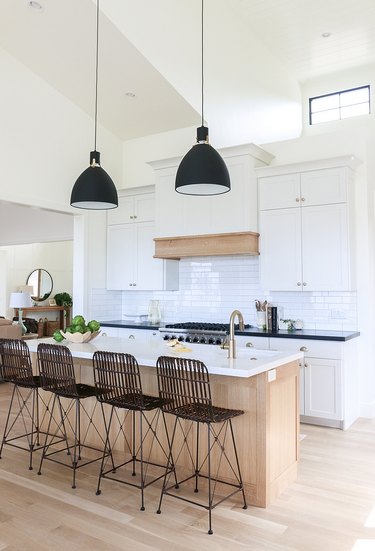 Industrial farmhouse kitchen with black pendant lights and linear bar stools