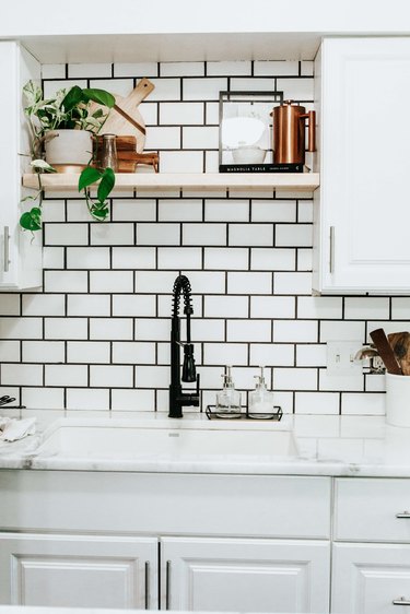 Industrial farmhouse kitchen with black faucet and black and white subway tile backsplash