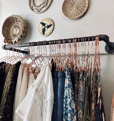 industrial closet ideas with copper hangers and boho baskets