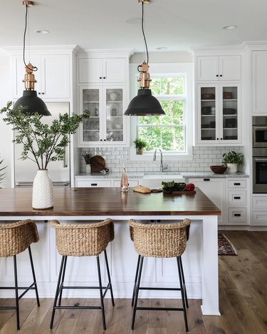 Industrial farmhouse kitchen with black metal pendant lights and seagrass bar stools