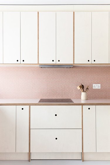 white kitchen cabinetry with pink mosaic kitchen backsplash