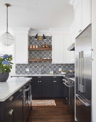 black kitchen backsplash with patterned tile and black cabinets and wood flooring