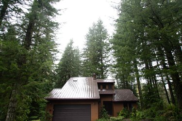 The three story chalet surround by woods.