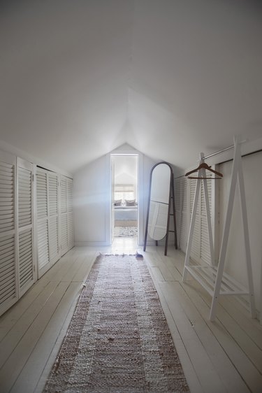 Attic Closet Ideas with standalone clothing rack and vintage runner