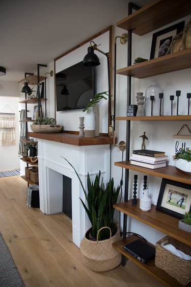Wood and metal shelves, fireplace, wood floors, basket, plant, and flat screen in industrial basement