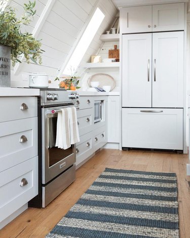 white attic kitchen with rug and stainless steel stove
