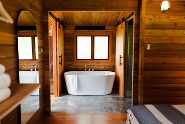 stand alone tub surrounded by natural wood and stone