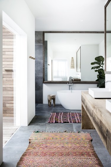 bathroom rug idea with two rugs and wood vanity topped by vessel sinks and freestanding bathtub