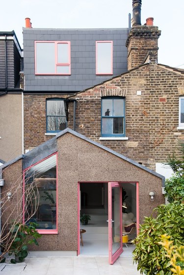 pink pivoting exterior back door with pink trim on brick home